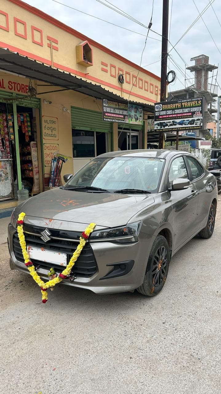 A photo of a Maruti Dzire New 2026 - Gray sedan with garland.
